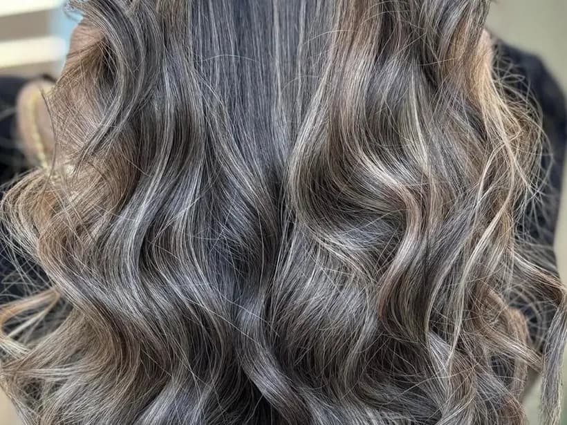 Balayage cendré sur base châtain, coupe mi-longue ondulée